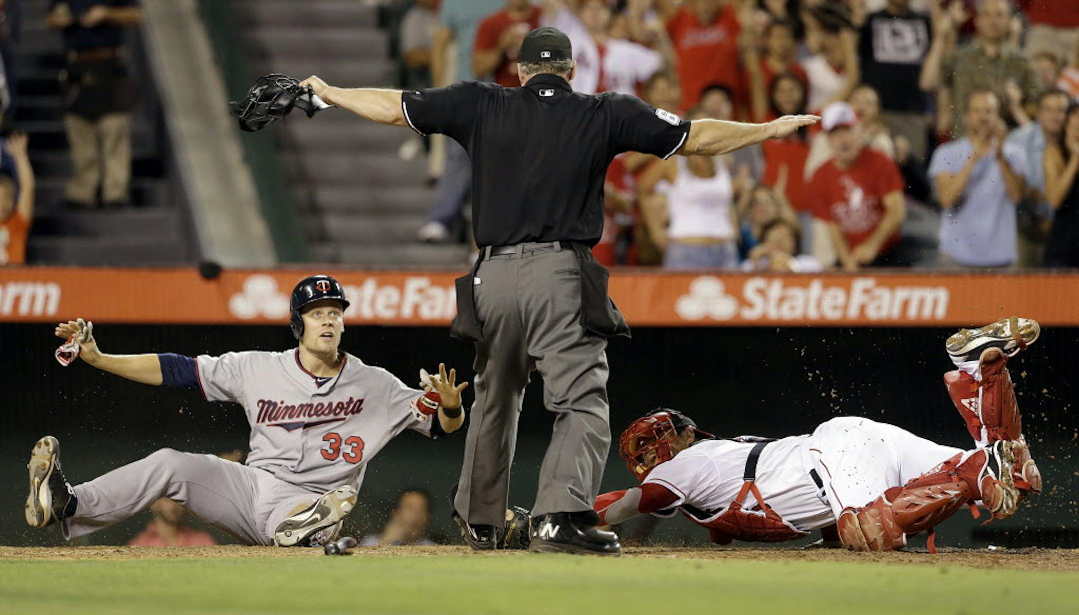 Justin Morneau scores on a Ryan Doumit double as Los Angeles catcher Hank Conger misses the tag and plate umpire Ted Barrett signals 'safe' in the eighth inning.
