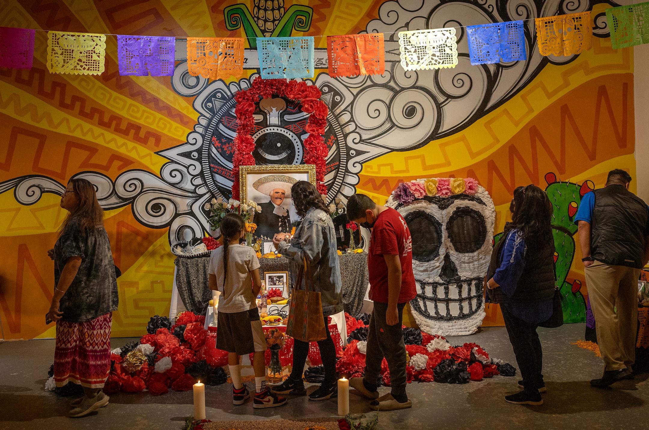 People make their way through many Dia De Los Muertos altars including a large one in honor of Mexican singer Vicente Fernandez at the celebration held at El Colegio High School, in Minneapolis, Minn., on Tuesday, Nov. 1, 2022. Multiple events around the Twin Cities area honored Dia De Los Muertos, a traditionally Mexican holiday that honors loved ones who have died.