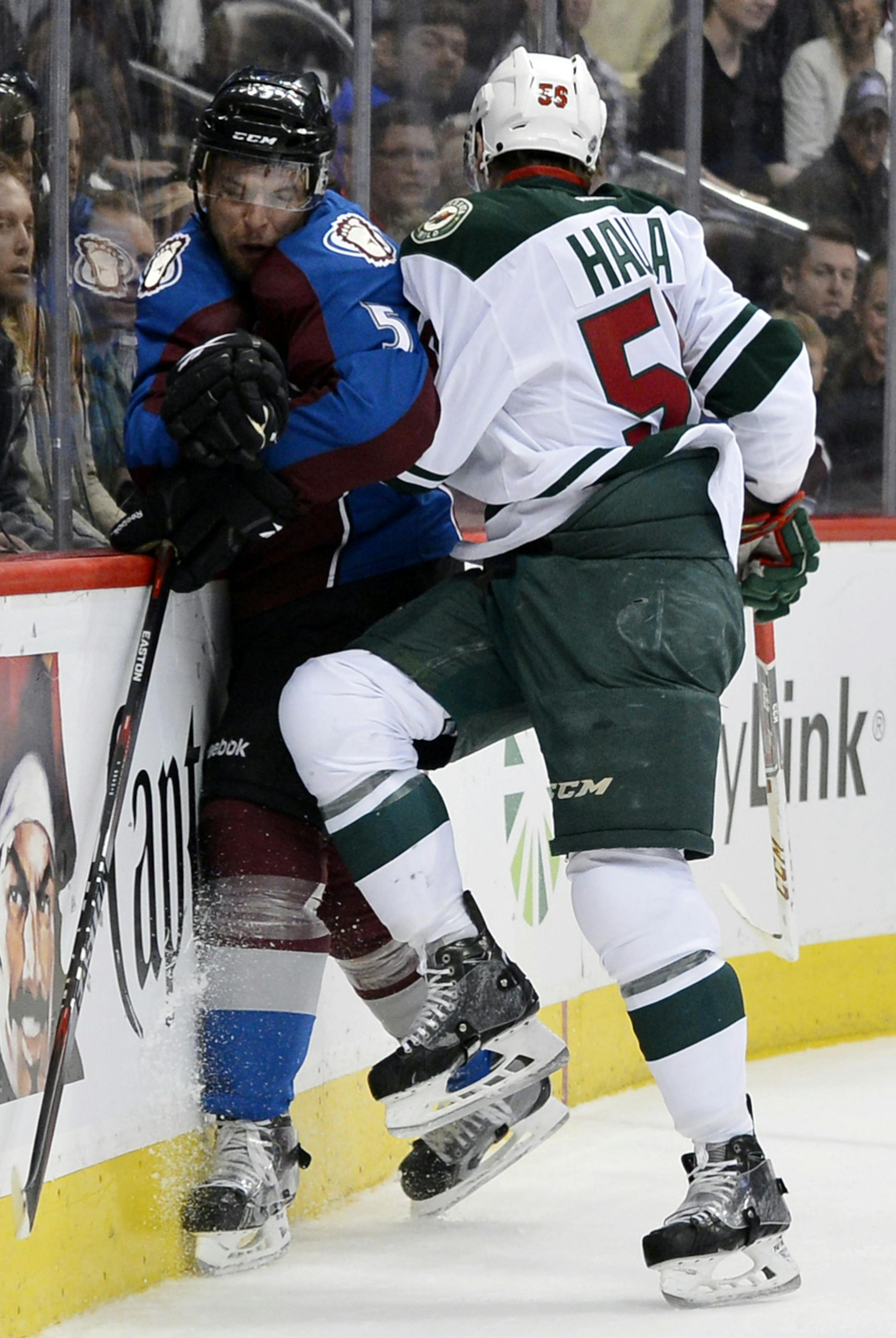 Minnesota Wild left wing Erik Haula (56) from Finland checks Colorado Avalanche defenseman Nate Guenin (5) into the boards in the first period of Game 2 of an NHL hockey first-round playoff series on Saturday, April 19, 2014, in Denver. (AP Photo/Jack Dempsey)