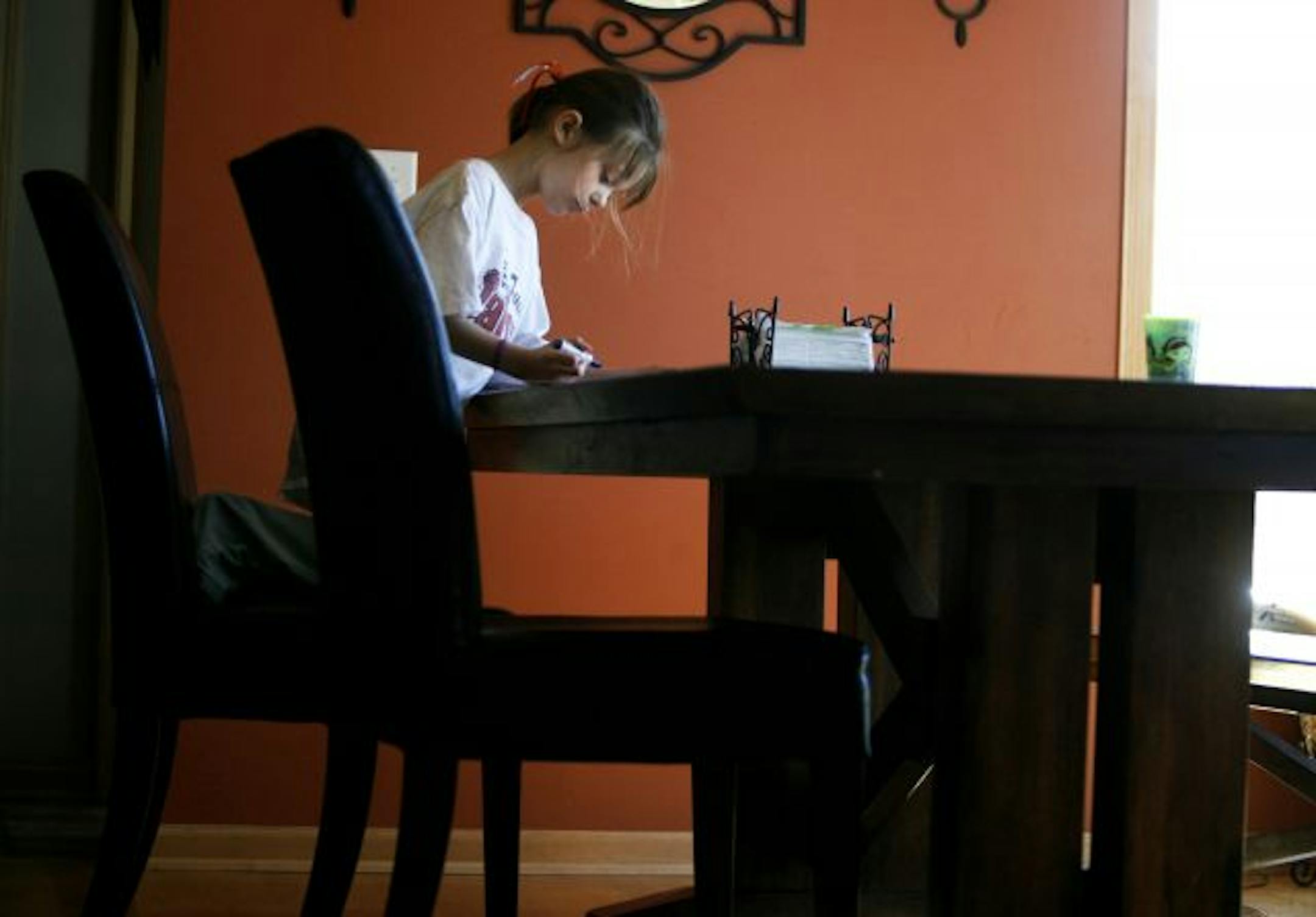 Starting while they're young: Lauren Wagner drew while using natural light only. Her family is one of three dozen in Elk River saving energy in Project Conserve. Among the steps the family has adopted: Keeping the water off while brushing teeth, below. "I'm 6 years old, and if I can do it everyone should do it," Lauren said.