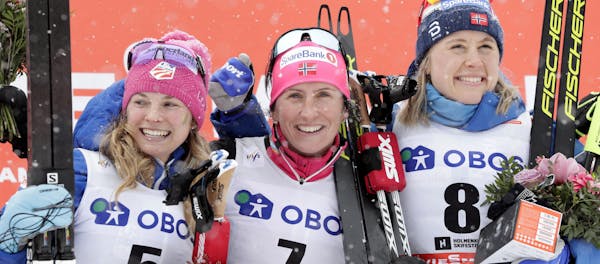Marit Bjoergen of Norway, center, winner of a cross-country ski, women's World Cup 30k Mass Start event, poses on the podium with second placed United