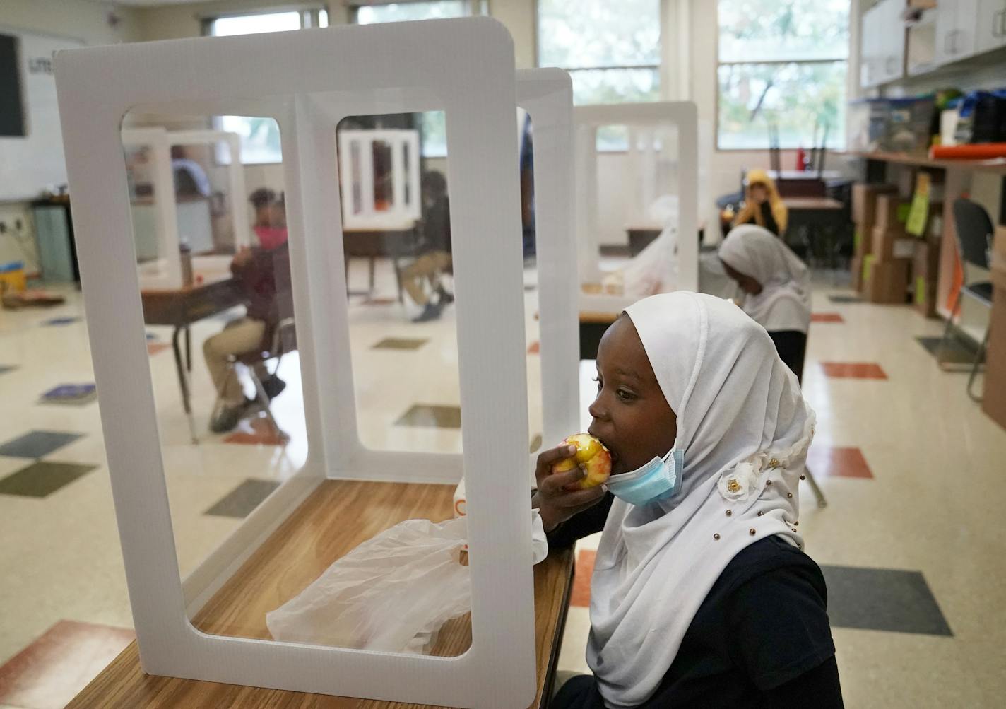 A kindergartner at Harvest Best Academy, a charter school in Minneapolis, ate an apple from her protective desk during lunchtime earlier in September.