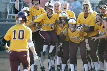 Jubilant Gophers players waited to greet Paige Palkovich (10) after her walk-off grand slam beat Arizona and kept the Gophers alive in the NCAA softba