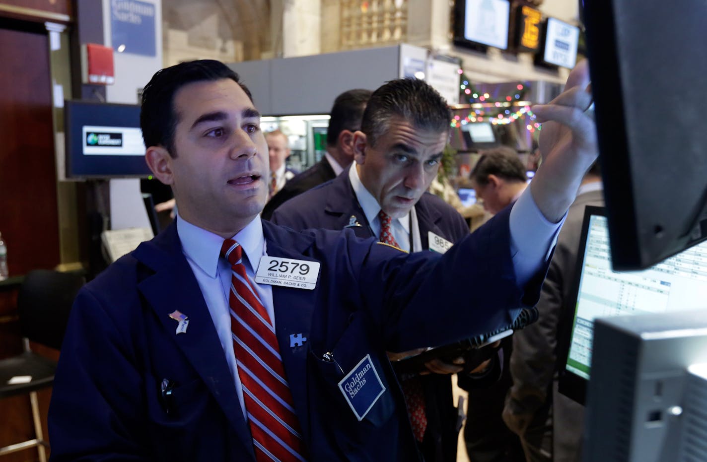 In this Monday, Dec. 16, 2013 photo, specialist William Geier, left, works on the floor of the New York Stock Exchange. Investors took to the sidelines Tuesday, Dec. 17, 2013, a day ahead of a key policy decision from the U.S. Federal Reserve that may see the central bank reduce its massive monetary stimulus