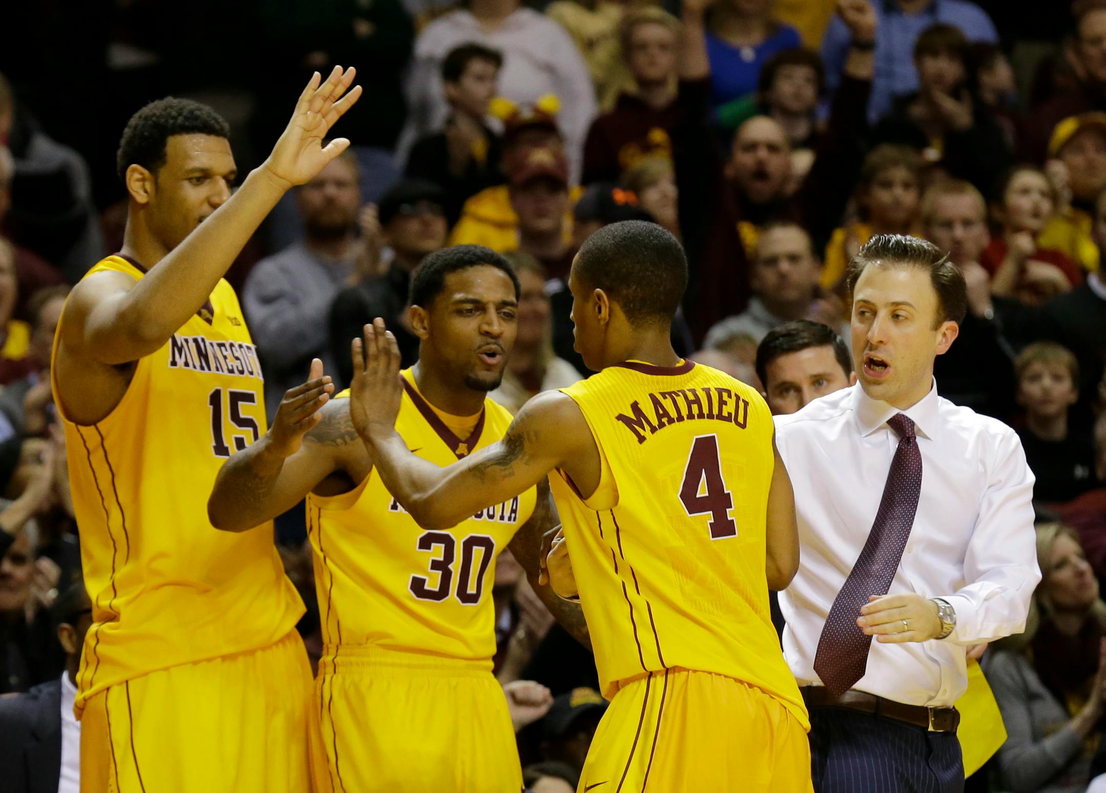 Minnesota guard DeAndre Mathieu (4) is congratulated by head coach Richard Pitino, right, Malik Smith (30) and Maurice Walker (15) as he comes out of the game during the final seconds against Indiana. The Gophers are on the bubble for the NCAA tournament.