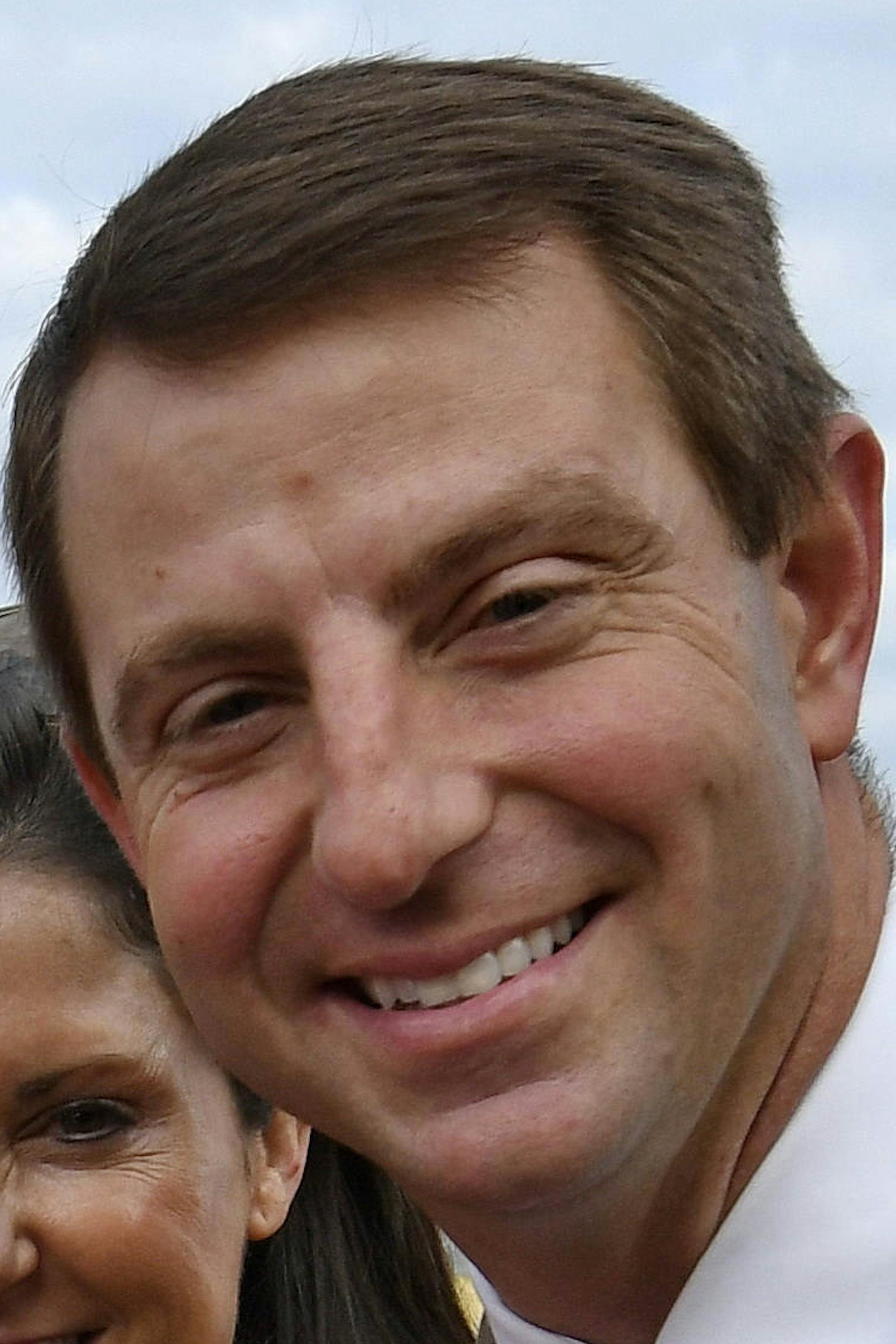 FILE - In this Jan. 14, 2017, file photo, Clemson head coach Dabo Swinney, right, with his wife Kathleen, and sons, Clay, Drew, and Will ride in a vintage car during a parade honoring the NCAA college football champions, in Clemson, S.C. Swinney has agreed to the biggest contract in college football history, paying him $92 million over the next 10 years. Trustees approved the contract Friday, April 26, 2019, which runs through 2028. (AP Photo/Richard Shiro, File)