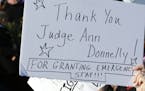 A woman holds a sign acknowledging a stay affecting immigrants trying to reach the United States issued late Saturday by New York Federal Judge Ann M.