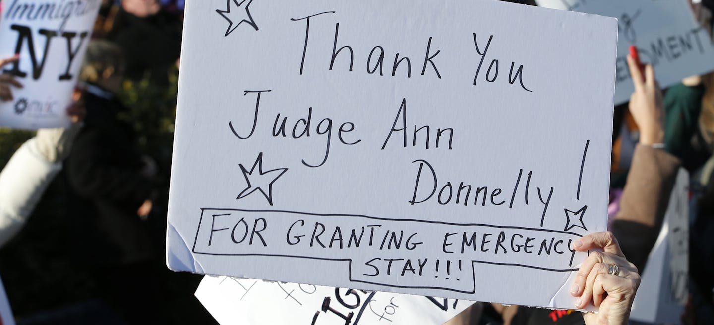 A woman holds a sign acknowledging a stay affecting immigrants trying to reach the United States issued late Saturday by New York Federal Judge Ann M. Donnelly, as they protest President Donald Trump's executive order banning immigrants from certain countries, Sunday, Jan. 29, 2017, in New York, as part of an immigrants' rights rally at Battery Park. (AP Photo/Kathy Willens) ORG XMIT: MIN2017013117302354