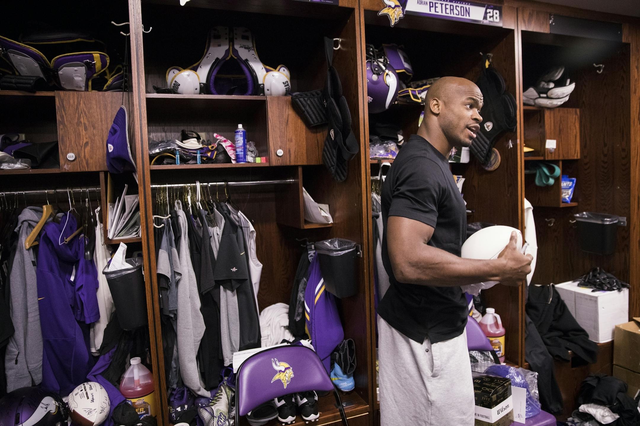 Adrian Peterson signs a football at his locker.