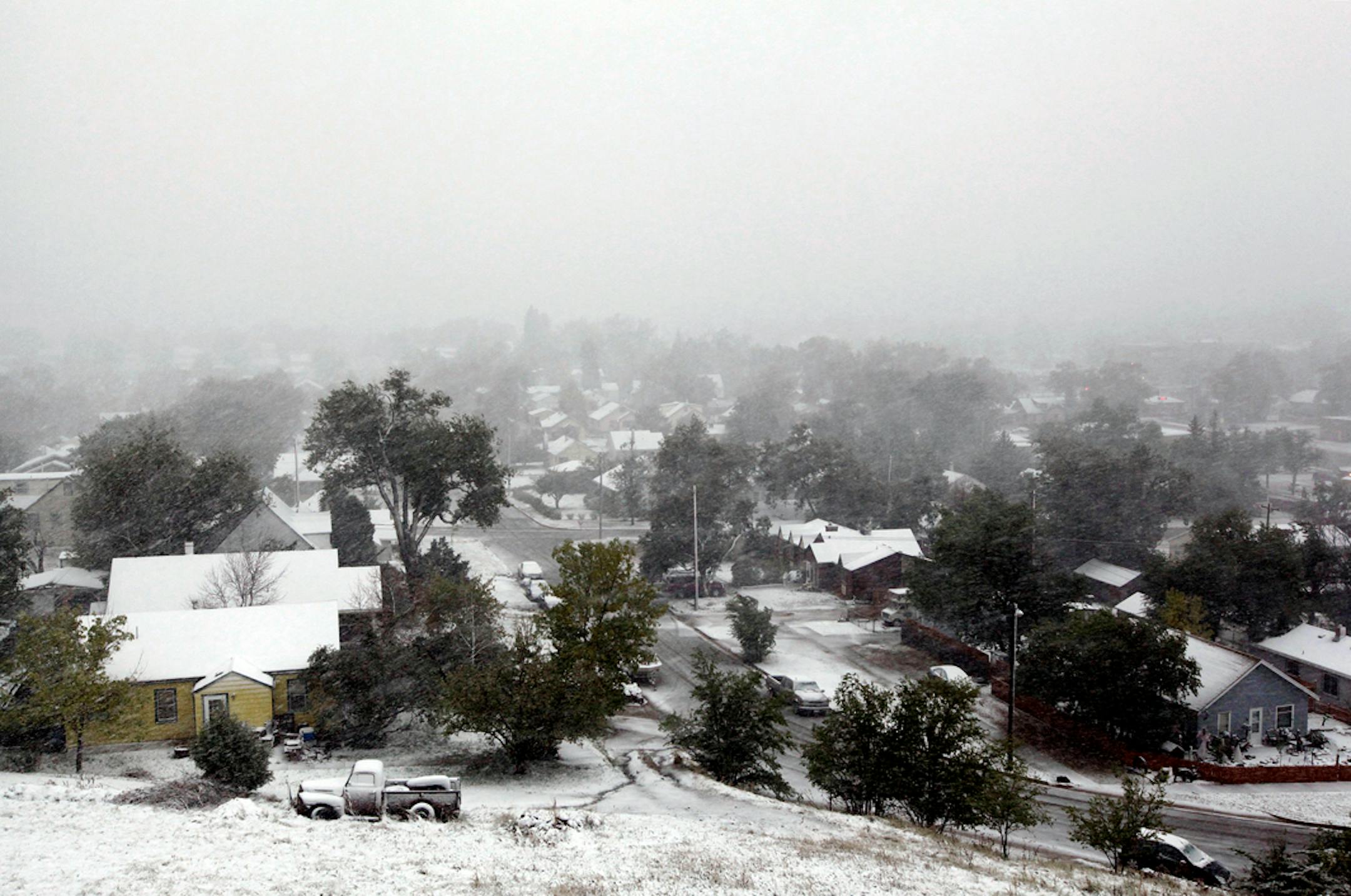 Snow falls over a residential neighborhood during a storm Friday, Oct. 4, 2013, in Rapid City, S.D. Blizzards rolled into parts of Wyoming and South Dakota on Friday, bringing the states to an unseasonably early wintery standstill by closing highways and schools. (AP Photo/Rapid City Journal, Benjamin Brayfield)