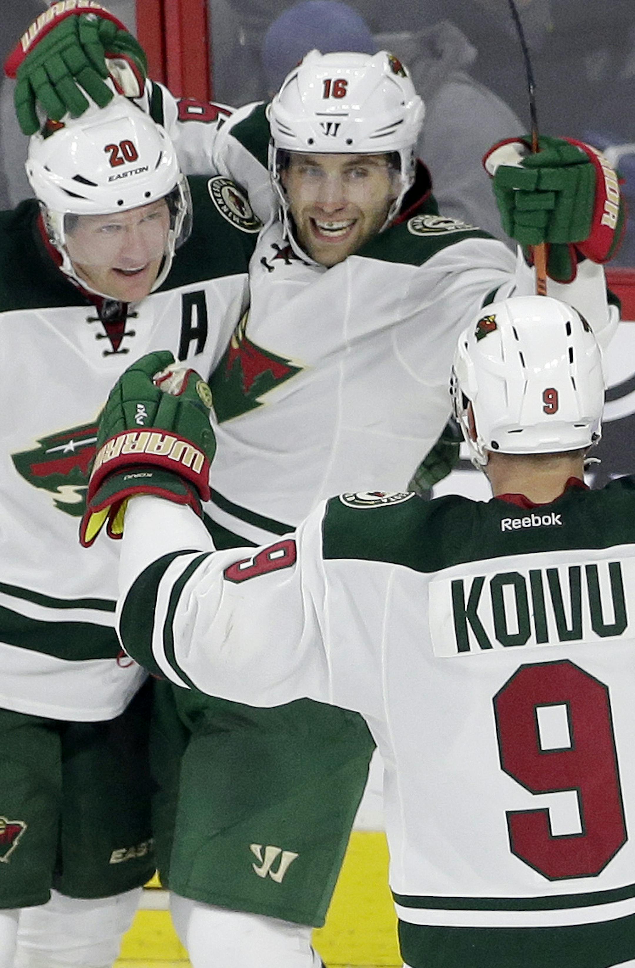 Minnesota Wild's Jason Zucker (16), Ryan Suter (20) and Mikko Koivu (9), of Finland, celebrate Zucker's winning goal against the Carolina Hurricanes during overtime in an NHL hockey game in Raleigh, N.C., Thursday, Nov. 12, 2015. Minnesota won 3-2. (AP Photo/Gerry Broome)