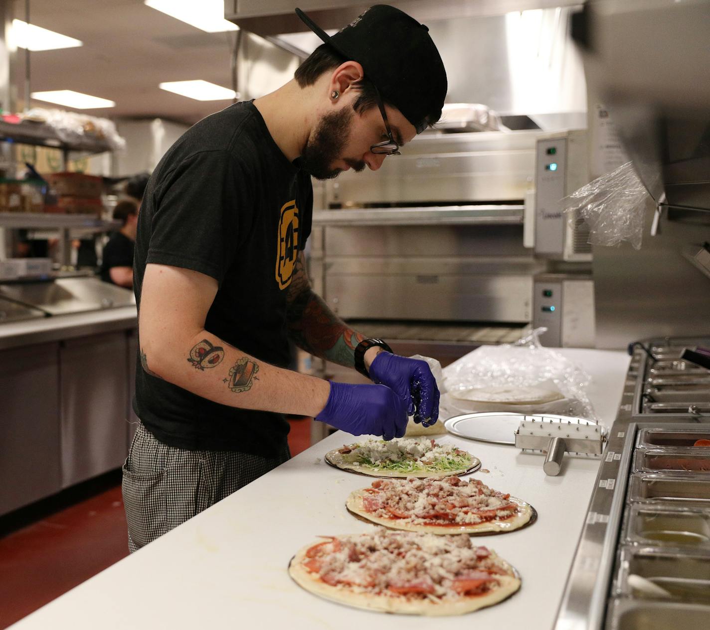 Kitchen Manager Cameron McGuire fixed a trio of pizzas in the kitchen at Alamo Drafthouse Cinema Tuesday. ] ANTHONY SOUFFLE &#xef; anthony.souffle@startribune.com Executives from Alamo Drafthouse Cinema gave a media tour of their first Twin Cities location opening soon Tuesday, July 17, 2018 in Woodbury, Minn. The Texas based chain touts a movie lovers experience with notable comfort food, craft beers, and state-of-the-art technology.