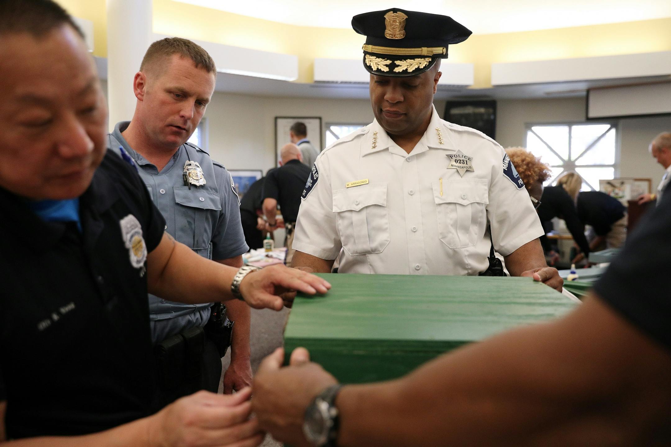 Police officer David O'Connor, second from left, looked on as Kou Vang, left, and Troy Dillard worked along with Police Chief Medaria Arradondo to build a free-standing Little Free Library Tuesday.
