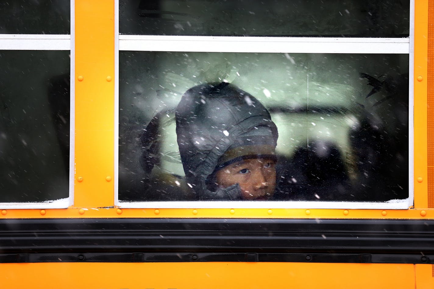 A child rides a bus to school in St. Paul during the first snowstorm of the season on Monday, November 10, 2014.