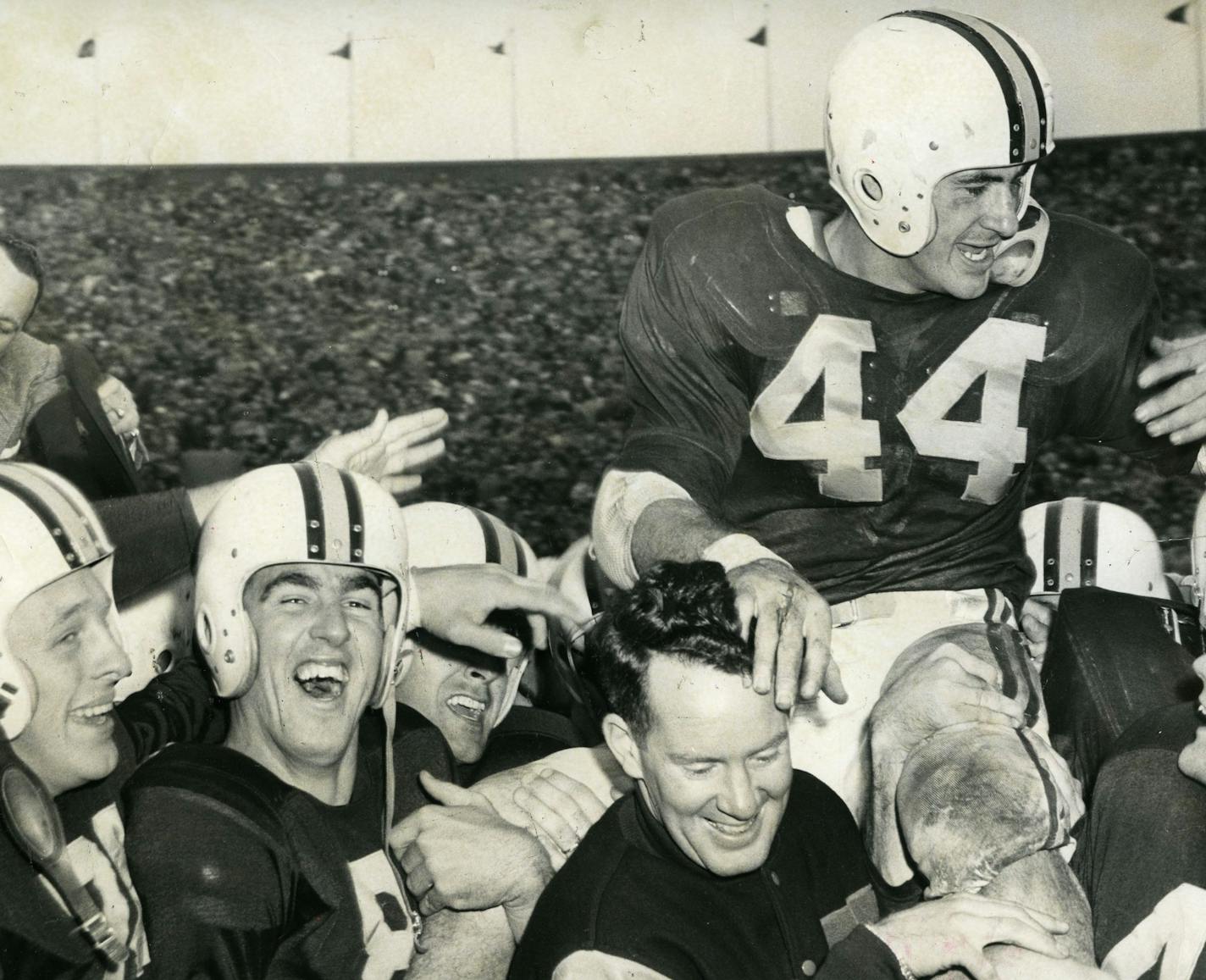 Bob McNamara, described as "touchdown ace" by the Minneapolis Tribune in this photo from Nov. 13, 1954, was carried off by the field by coach Murray Warmath and Gophers teammates after returning a kickoff 89 yards for a score in Minnesota's 22-20 victory over Iowa.