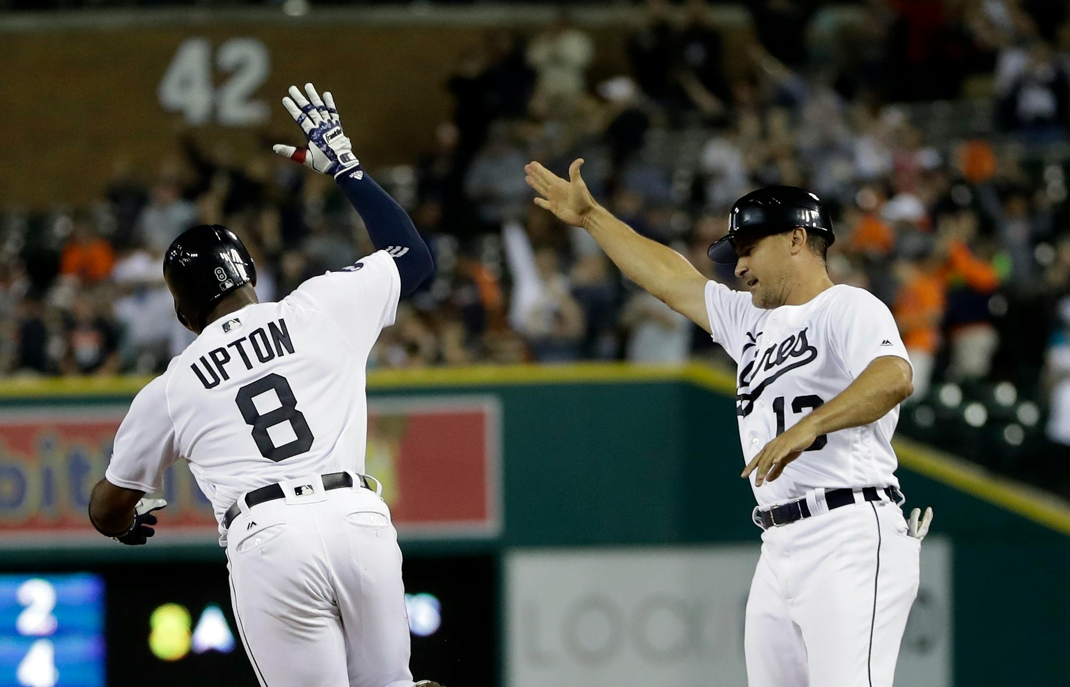 Detroit Tigers' Justin Upton (8) is high-fived by first base coach Omar Vizquel after hitting a walk-off two-run home run during the ninth inning of a baseball game against the Minnesota Twins, Saturday, Aug. 12, 2017, in Detroit. (AP Photo/Carlos Osorio)
