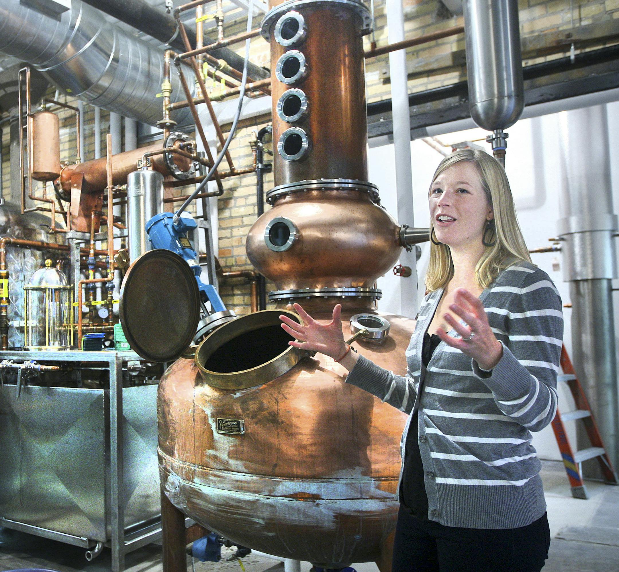 ADVANCE FOR WEEKEND EDITIONS NOV. 23-24 - In this Nov. 4, 2013 photo, Emily Vikre explains how the distilling process works at Vikre Distilleries in Duluth, Minn.. At left is the stripping still where a mixture of grains and yeast are cooked to create the first run of spirits. These are refined in the copper spirit still to her left. (AP Photo/The Duluth News-Tribune, Bob King) ORG XMIT: MIN2013112318024712