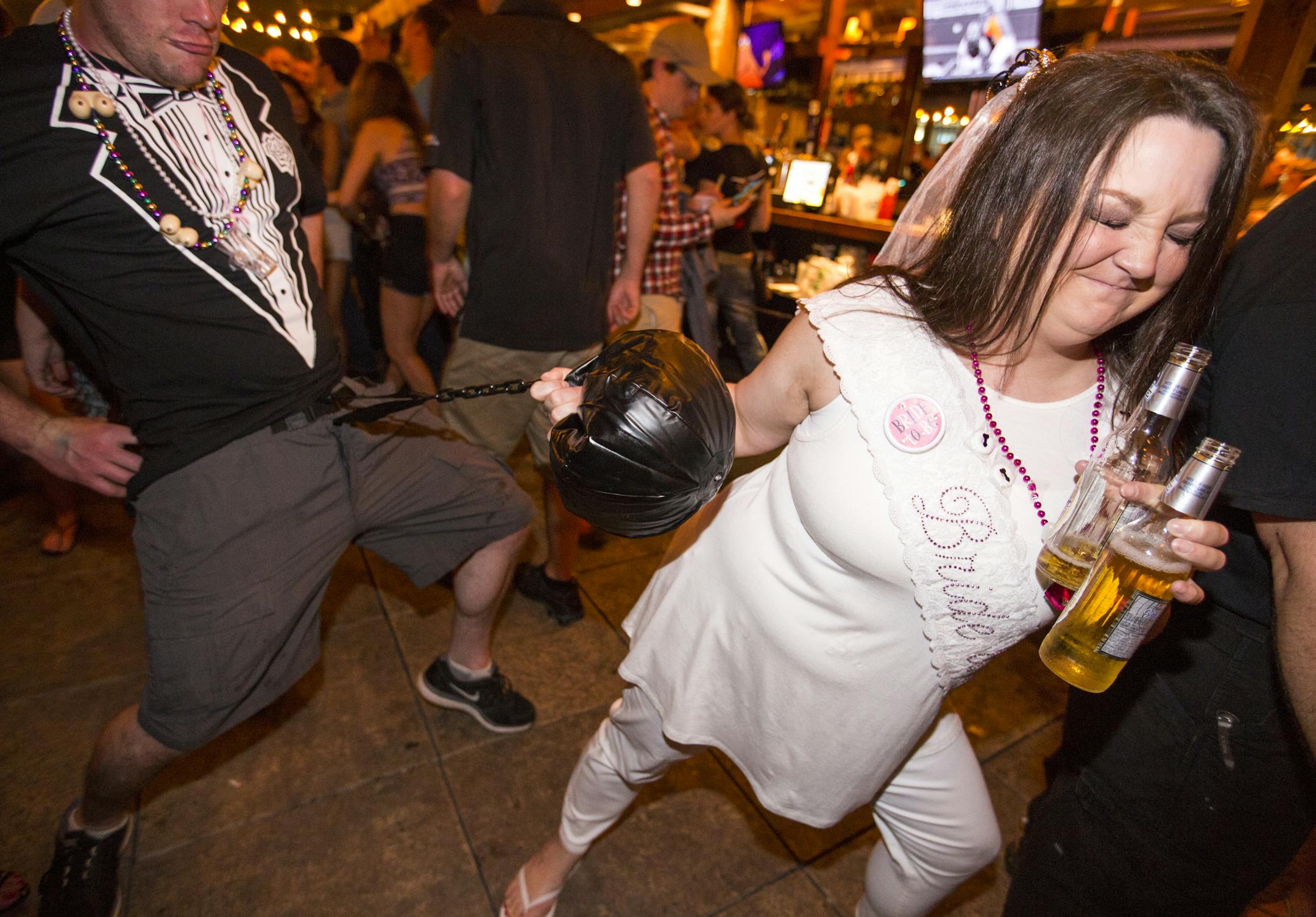 Bride-to-be Andrea Buzay plays with a fake ball and chain with members of a separate bachelor party during her bachelorette party at Cowboy Jack's in downtown Minneapolis on Saturday, June 20, 2015. ] LEILA NAVIDI leila.navidi@startribune.com /
