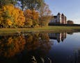People walks next to a medieval castle among seasonal coloured trees on an autumn day in Mir, Belarus, 95 kilometers (60 miles) west of Minsk, Sunday,