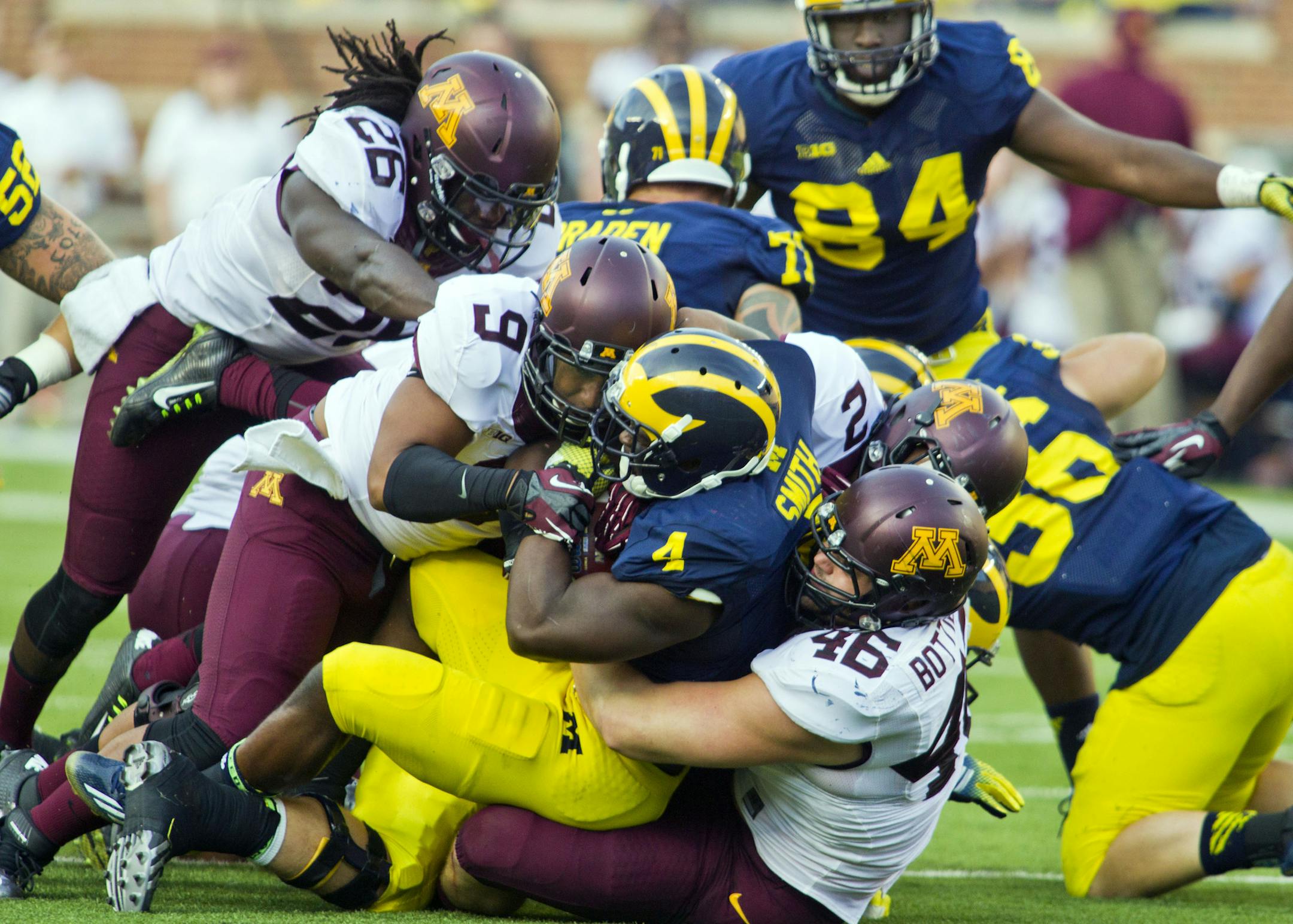 Michigan running back De'Veon Smith (4) gets gang-tackled by Minnesota defensive lineman Alex Keith (9), defensive lineman Cameron Botticelli (46) and others in the third quarter of an NCAA college football game in Ann Arbor, Mich., Saturday, Sept. 27, 2014. Minnesota won 30-14. (AP Photo/Tony Ding)