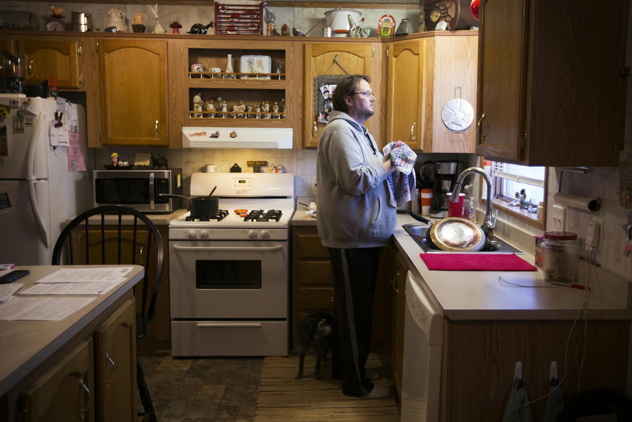 Unemployed miner Douglas Whitney does the dishes after making dinner for his wife and daughter at home in Hibbing.
