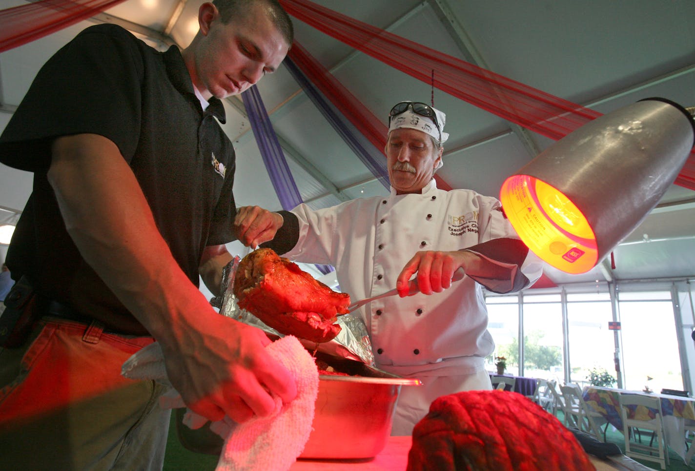 Server Mark O'Neill held a tray while Joe Nagelin, executive chef of Oakdale-based Prom Catering, grabbed a carving turkey during brunch in the Pro-Am tent on the first day of the 3M Championship senior PGA event, being held this week in Blaine. Prom Catering is handling the food for 37 PGA events this year.