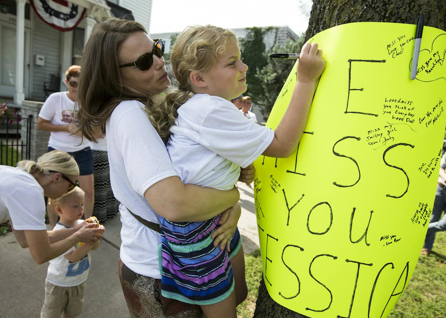 Amber Peltier holds up her daughter Ainsley Kummrow, 6, to write a message to Jessica Hanson during a memorial. Peltier's husband is Jessica's cousin. ] (Leila Navidi/Star Tribune) leila.navidi@startribune.com BACKGROUND INFORMATION: The family of Jessica Hason, 24, a cyclist who was hit and killed by a motorist at 28th Street and Pleasant Avenue in Minneapolis three years ago, holds a memorial for Jessica where she was killed on Tuesday, July 19, 2016. The driver will be sentenced today.