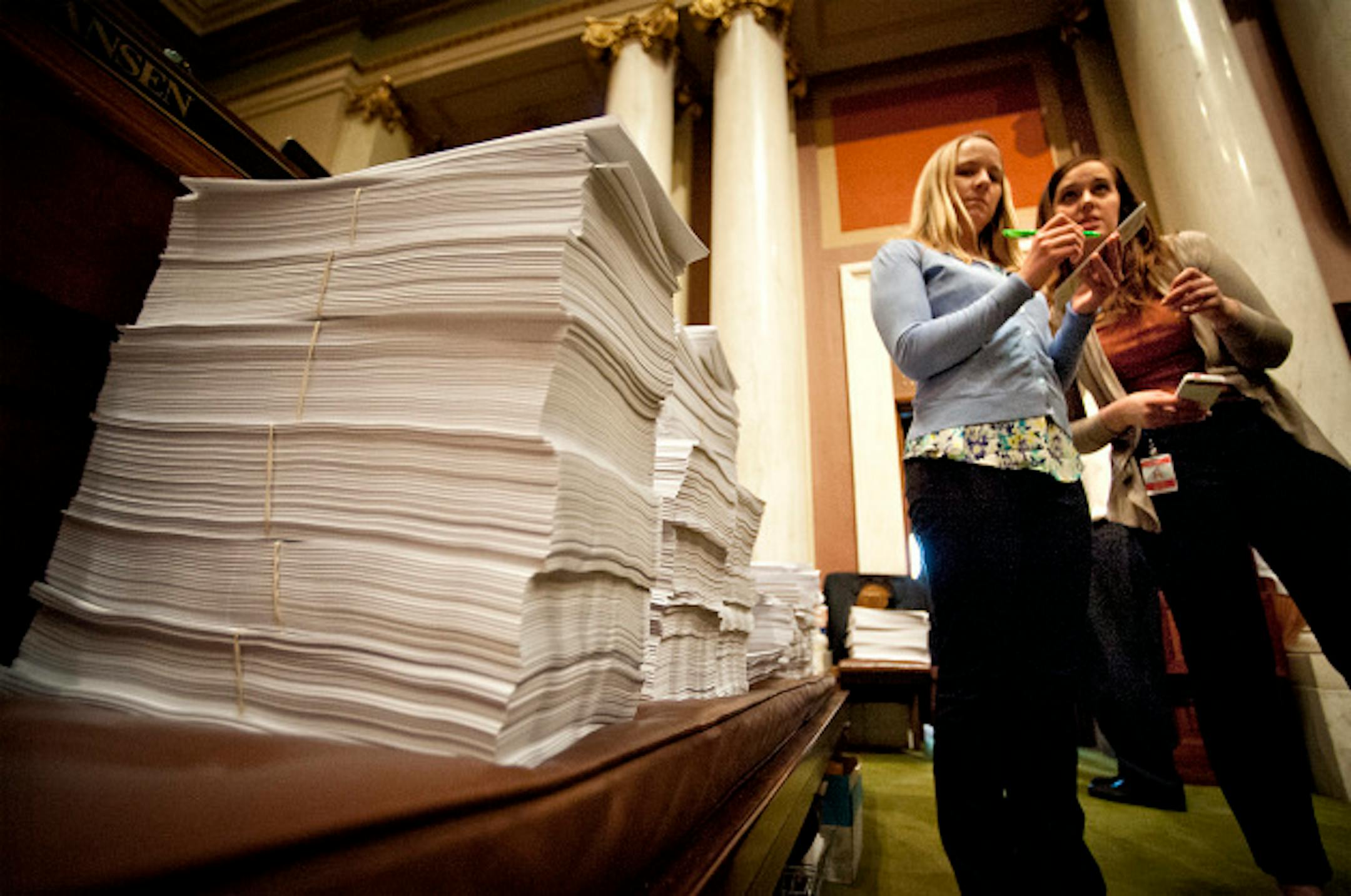 Stacks of printed bills and amendments at the start of Saturday's debate.  With only 3 days left in the legislative schedule the House was set to debate a list of bills including childcare unionization Saturday, May 18, 2013  On the right DFL staffers Sasha Bergman and Jessica Nyman prepared for the start of the session.     ]   GLEN STUBBE * gstubbe@startribune.com