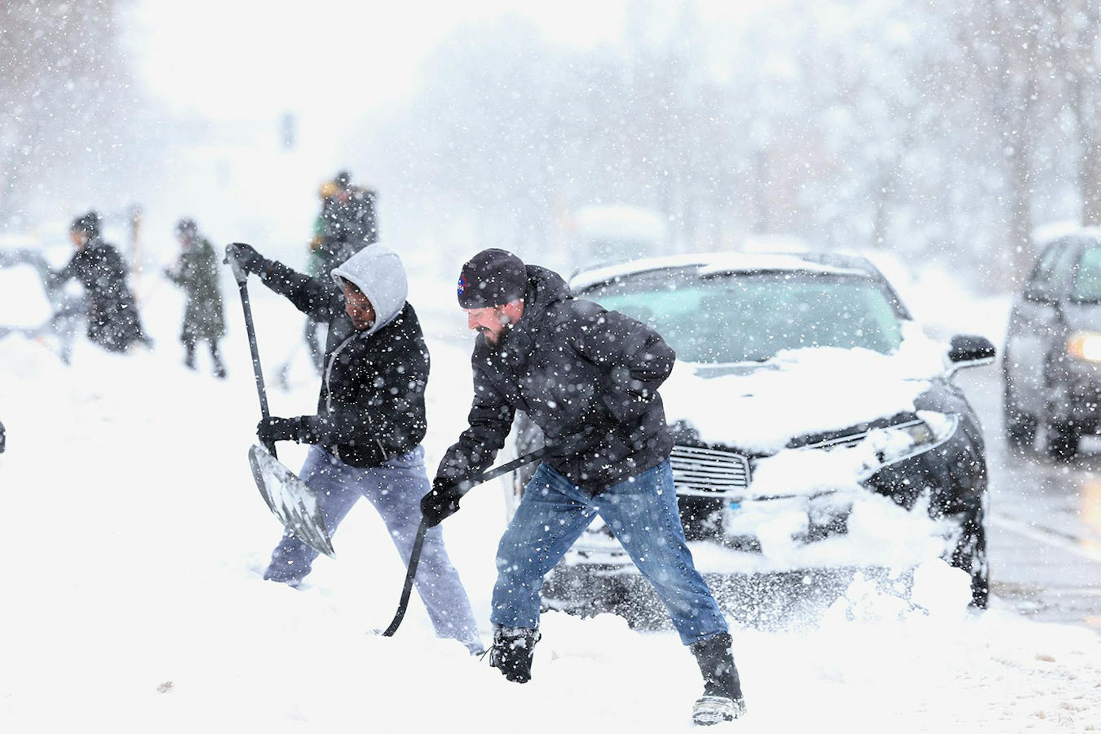 Neighbors John Bauer, right, and Fahmi Osman helped residents in the 3200 block of Portland Avenue dig their cars out.
