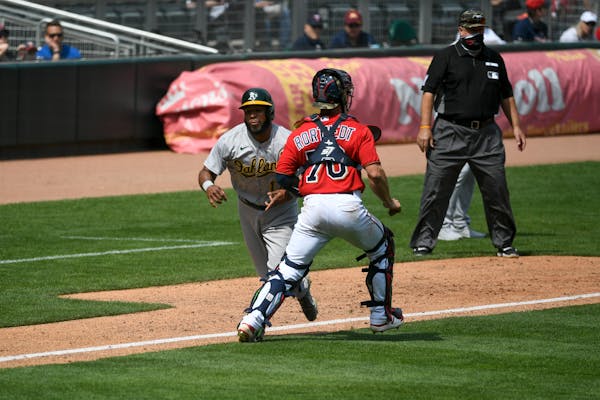 Minnesota Twins catcher Ben Rotvedt, right, makes contact with Oakland Athletics Elvis Andrus and is called for interference allowing Andrus to score 