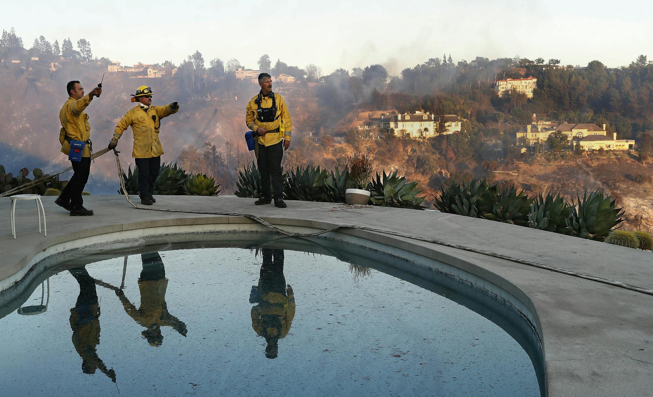 From left, Florin Sarbu, Dan Smithers, and Robert Caropino of the Los Angeles City Fire Dept. monitor the Skirball fire, from the backyard of a home on Casiano Rd., east of Sepulveda Blvd in Los Angeles on Dec. 6, 2017. The brush fire broke out Wendesday morning near Getty Center in the Sepulveda Pass, prompting the closure of the Northbound 405 Freeway and led to some mandatory evacuations in the area. (Mel Melcon/Los Angeles Times/TNS) ORG XMIT: 1217896