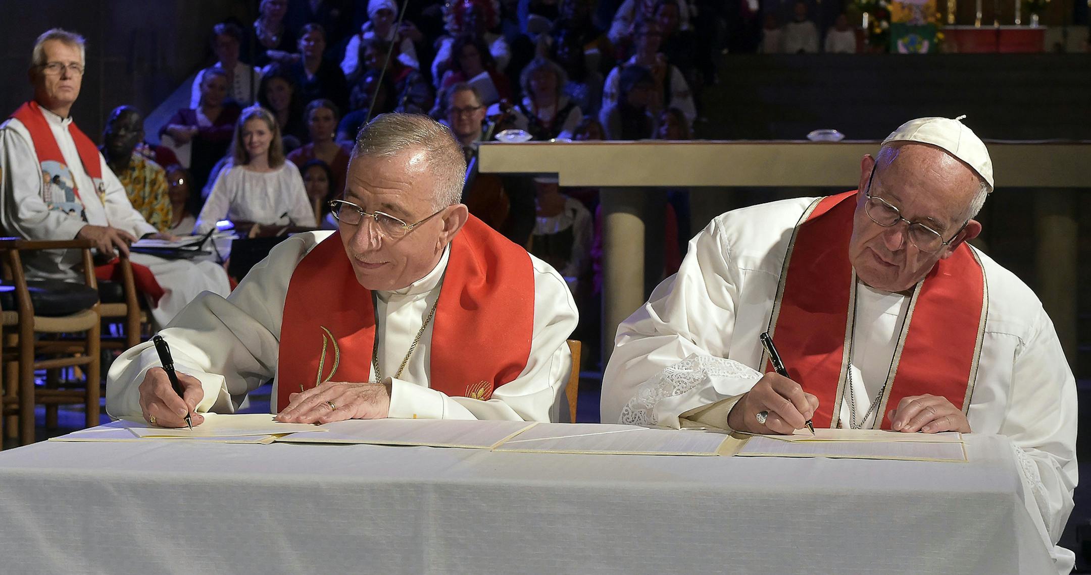 Pope Francis, right, and the President of the Lutheran World Federation Bishop Munib Younan sign a joint declaration during an ecumenical prayer in the Lund Luteran cathedral, Sweden, Monday, Oct. 31, 2016. Francis traveled to secular Sweden on Monday to mark the 500th anniversary of the Protestant Reformation, a remarkably bold gesture given his very own Jesuit religious order was founded to defend the faith against Martin Luther's "heretical" reforms five centuries ago. (L'Osservatore Romano/P