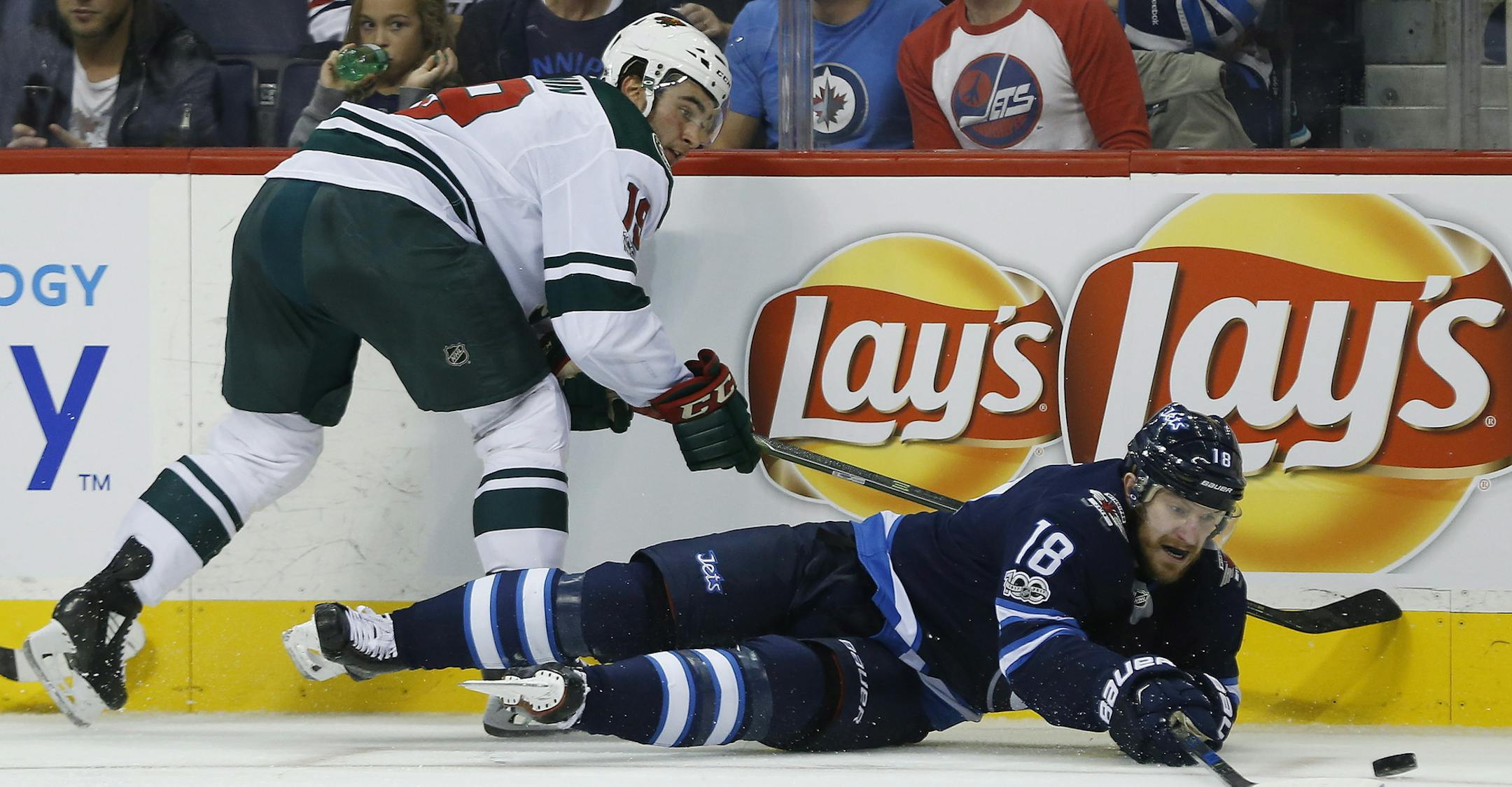 Winnipeg Jets' Bryan Little (18) plays the puck after getting hit by Minnesota Wild's Luke Kunin (19) during the second period of an NHL hockey game Friday, Oct. 20, 2017, in Winnipeg, Manitoba. (John Woods/The Canadian Press via AP) ORG XMIT: MIN2017102021384759