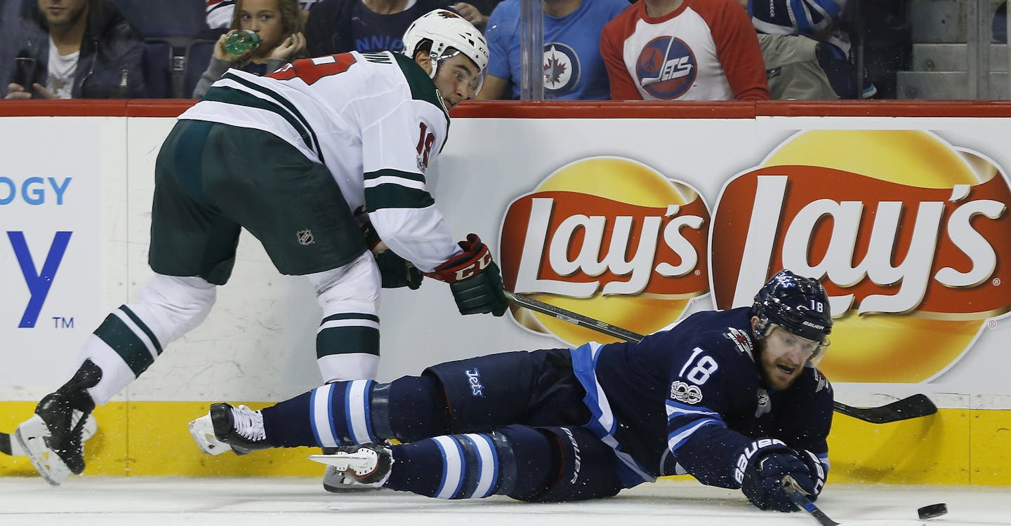 Winnipeg Jets' Bryan Little (18) plays the puck after getting hit by Minnesota Wild's Luke Kunin (19) during the second period of an NHL hockey game Friday, Oct. 20, 2017, in Winnipeg, Manitoba. (John Woods/The Canadian Press via AP) ORG XMIT: MIN2017102021384759