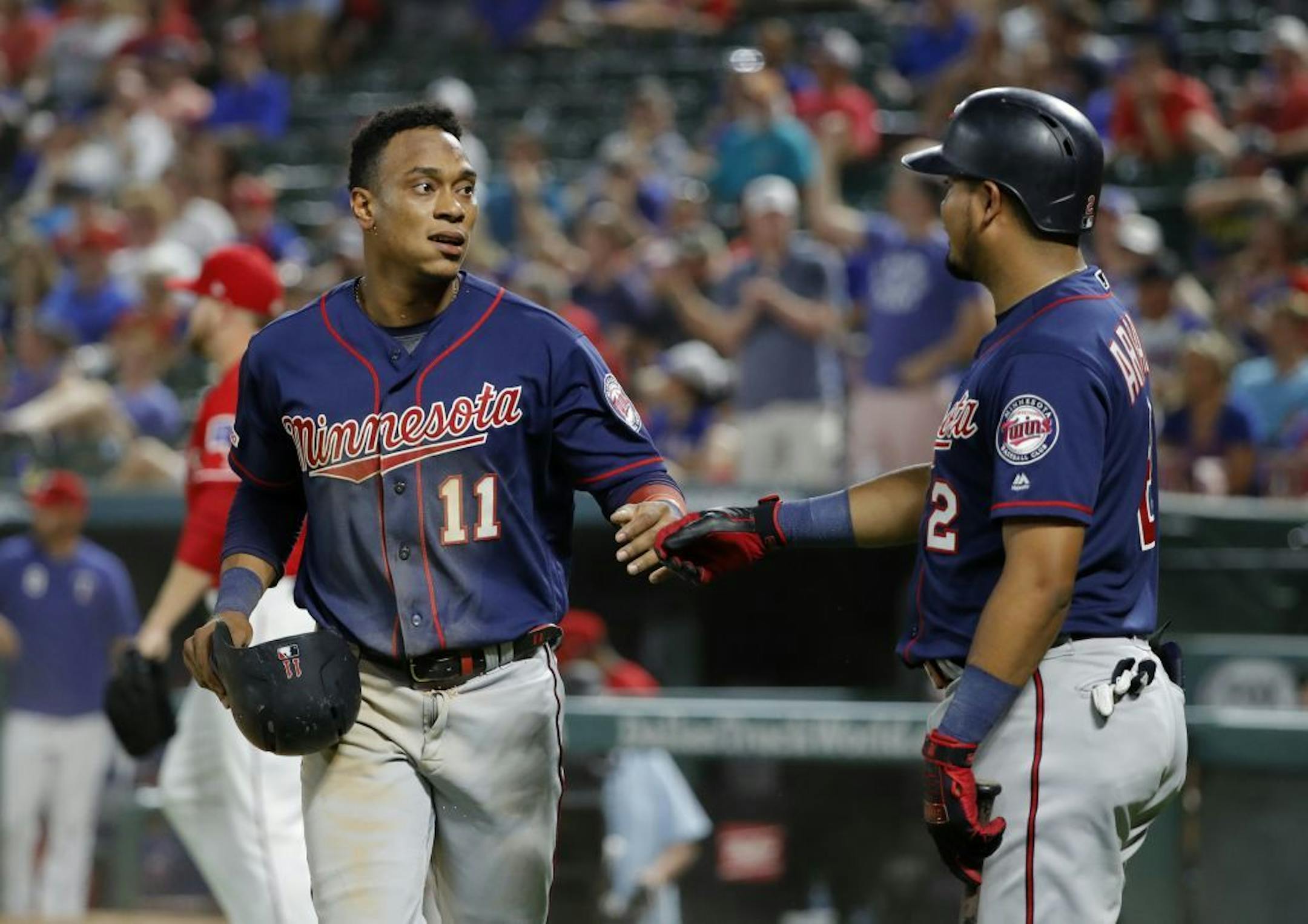 Minnesota Twins' Jorge Polanco (11) and Luis Arraez (2) celebrate after Polanco scored during the eighth inning of the team's baseball game against the Texas Rangers in Arlington, Texas, Saturday, Aug. 17, 2019.