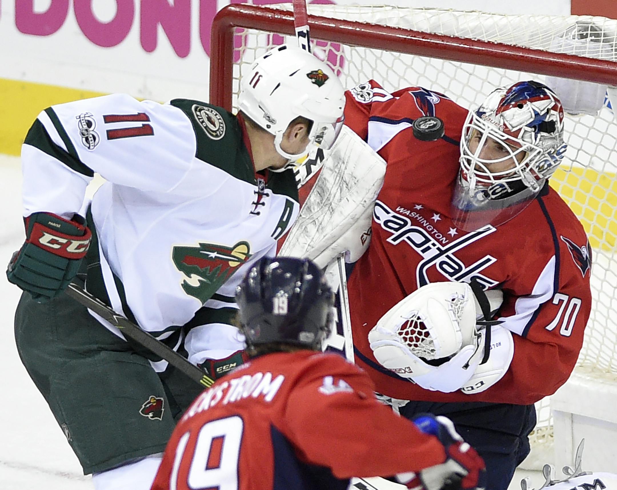 Washington Capitals goalie Braden Holtby (70) looks at the puck against Minnesota Wild left wing Zach Parise (11) during the third period of an NHL hockey game, Tuesday, March 14, 2017, in Washington. The Capitals won 4-2. Also seen is Washington Capitals center Nicklas Backstrom (19), of Sweden. (AP Photo/Nick Wass)
