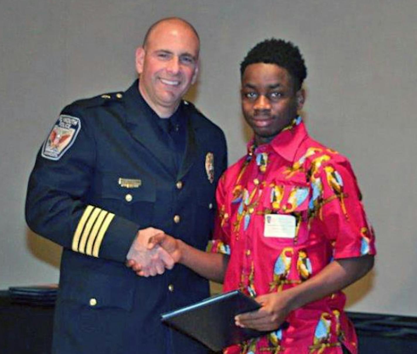 Plymouth Public Safety Director Mike Goldstein gives 17-year-old Urias Jah a Citizens Award on March 3. City officials commended the teen for his extraordinary effort in extinguishing a fire that erupted at an apartment complex last fall. City of Plymouth credit.