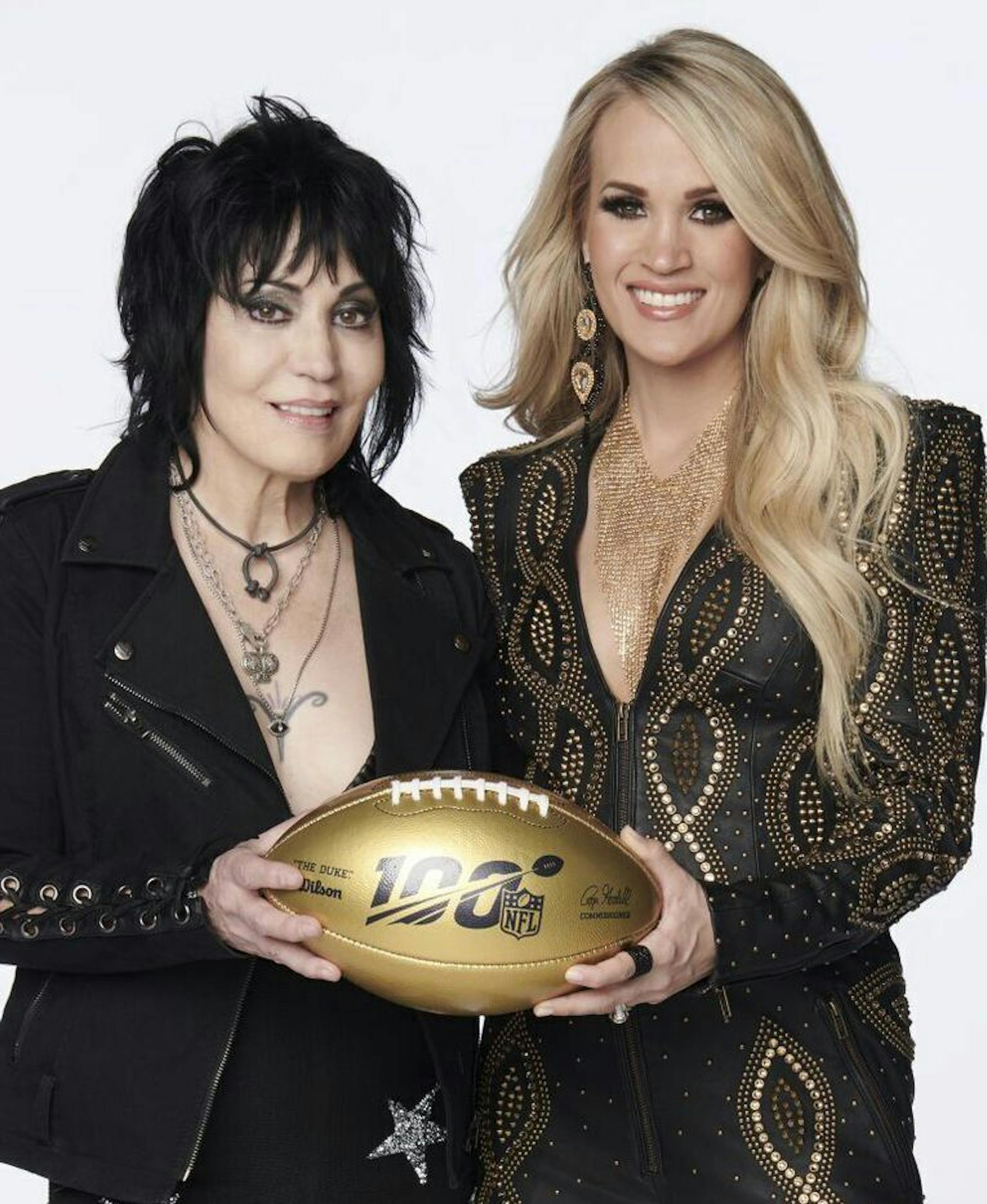 In this photo provided by NBC Sports, Joan Jett, left, and Carrie Underwood pose with a 100th anniversary NFL football. NBC's Sunday Night Football open will return to the original Waiting All Day for Sunday Night song, but this time Carrie Underwood will be joined by Rock & Roll Hall of Fame inductee Joan Jett. Her band, the Blackhearts, also perform in the open, which features NFL stars. (Virginia Sherwood/NBC Sports via AP)