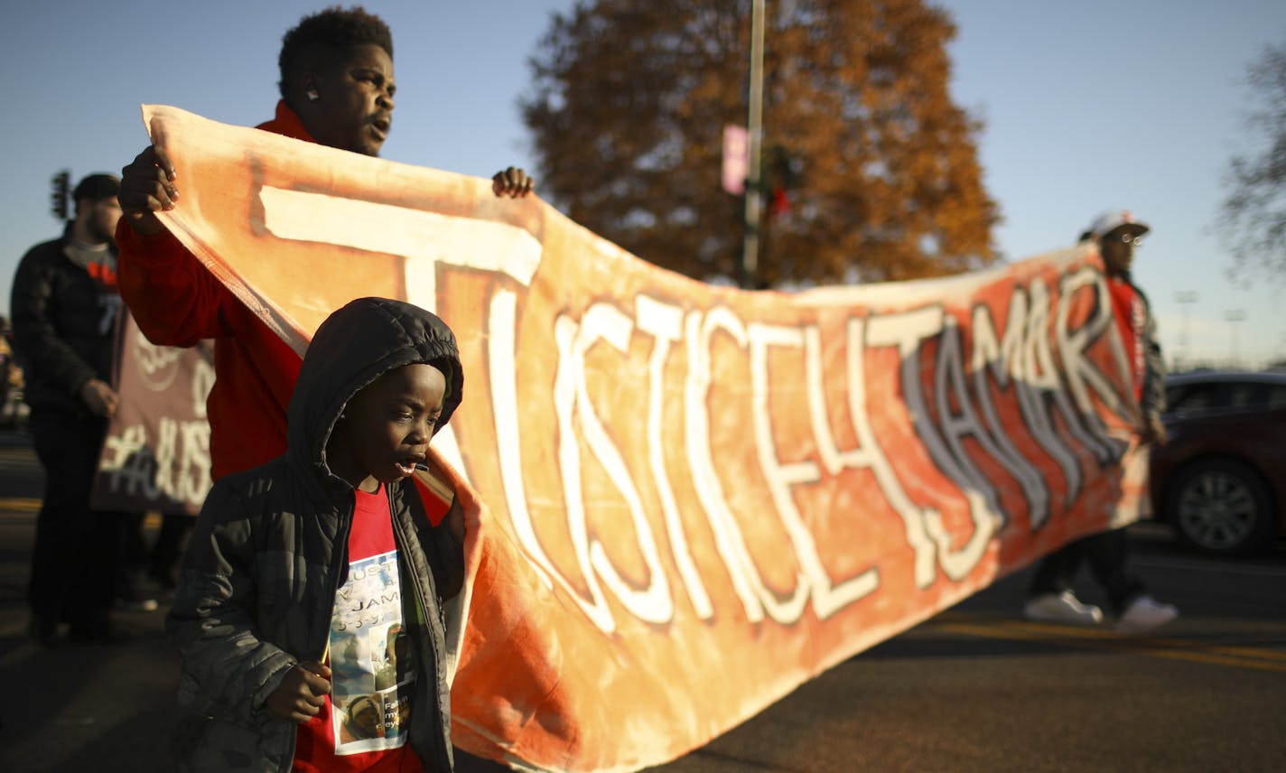 Quincy Hill and his son, Quincy Jr. helped carry a banner as people began marching west on Broadway Ave. after a gathering to remember Jamar Clark's death Sunday afterrnoon. Both are cousins of Clark. ] JEFF WHEELER &#x2022; jeff.wheeler@startribune.com A week of events began Sunday, November 13, 2016 to honor Jamar Clark, who was killed by Minneapolis Police a year ago Tuesday. About 75 people gathered in the Cub Foods parking lot on Broadway Ave. and after listening to a few speakers, includin