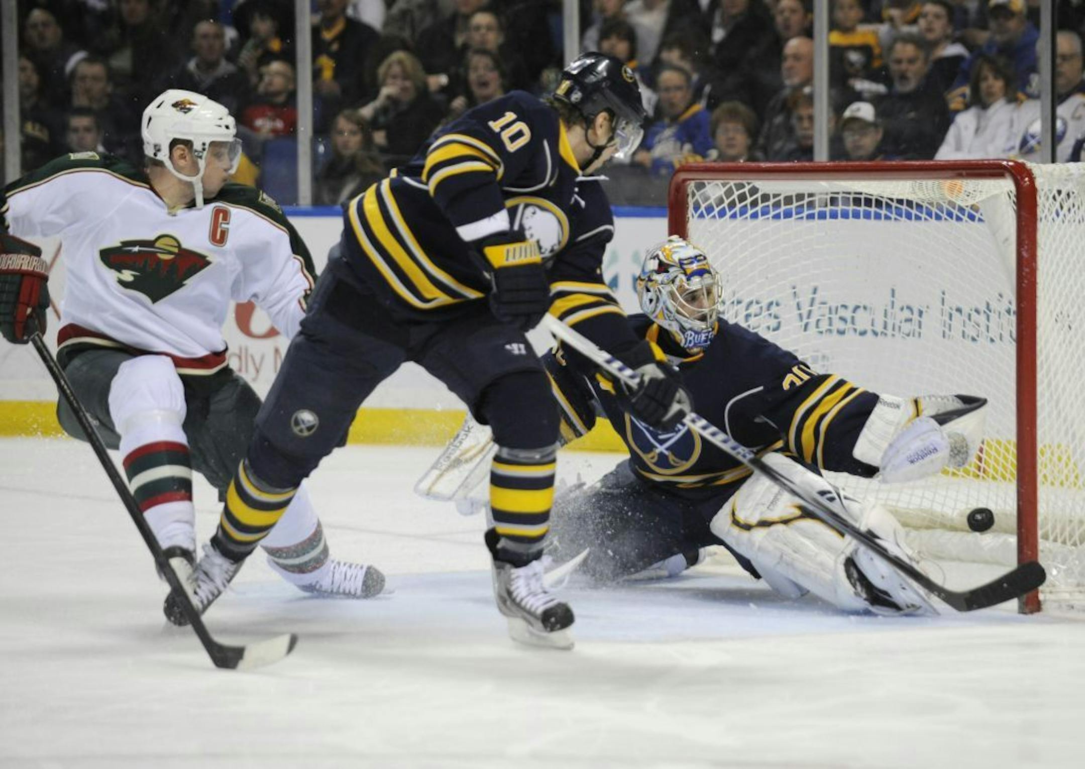 Minnesota Wild Mikko Koivu (9) of Finland, deflects the puck as Buffalo Sabres' Christian Ehroff (10) of Germany, and goaltender Ryan Miller (30) defend during the second period of an NHL hockey game in Buffalo, N.Y., Saturday, March 24, 2012.