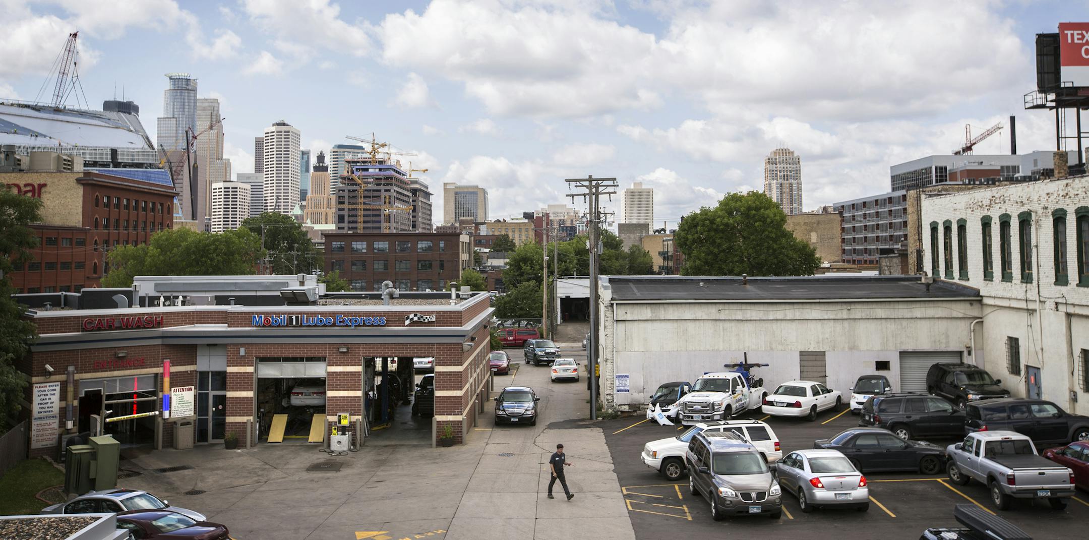 Cars drive to and from 12th Avenue South at Bobby and Steve's Auto World on Friday, August 7, 2015. The owners of Bobby and Steve's Auto World would like to demolish the white building on the right to give more room for cars to drive in and out from 12th Avenue South, which is not currently wide enough for two cars to pass each other. ] LEILA NAVIDI leila.navidi@startribune.com / BACKGROUND INFORMATION: Friday, August 7, 2015.The most prominent gas station near downtown Minneapolis wants to make