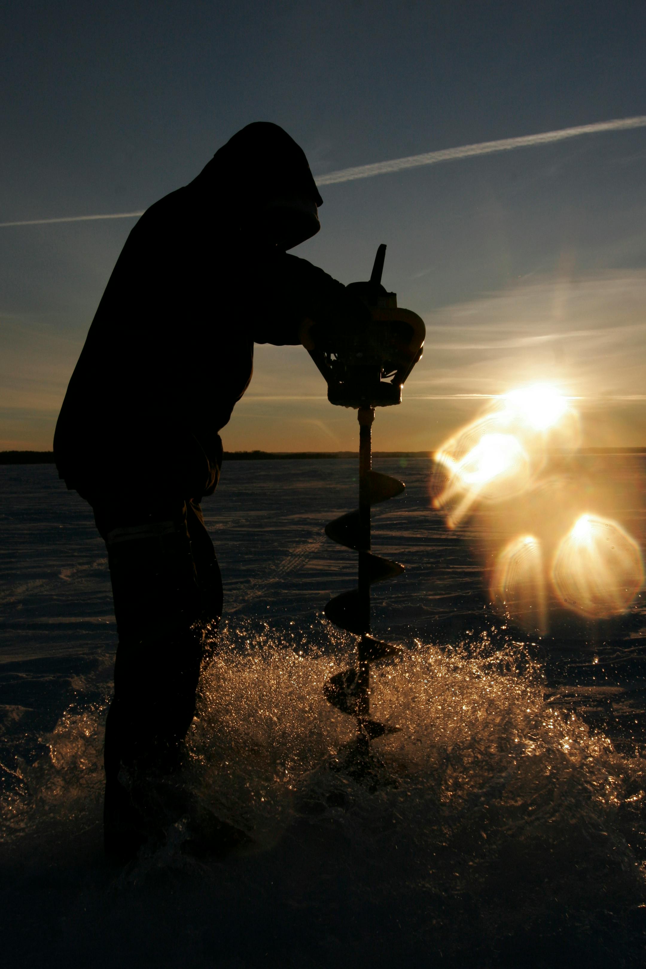 The setting sun reflects off the camera lens as Nate Rendulich of Duluth pulled up an auger full of water after drilling an ice fishing hole on Leech Lake. ORG XMIT: MIN1402051133091597 ORG XMIT: MIN1412021035531351
