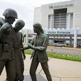 FILE - In this June 9, 2014 file photo is a sculpture portraying a wounded soldier being helped on the grounds of the Minneapolis VA Hospital. Minnesota’s Veterans Affairs clinics and hospitals fare slightly better in delivering timely care to veterans than the national average between September and February, according to six months of appointment data analyzed by the Associated Press. (AP Photo/Jim Mone, File) ORG XMIT: MIN2015051314130372 ORG XMIT: MIN1505131416040110