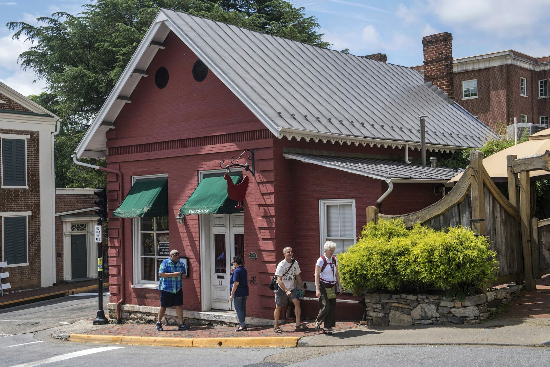 People walk past the Red Hen restaurant in Lexington, Va., Wednesday, June 27, 2018. The co-owner of the Virginia restaurant that refused to serve White House press secretary Sarah Huckabee Sanders has resigned from a local business group. (AP Photo/Don Petersen)