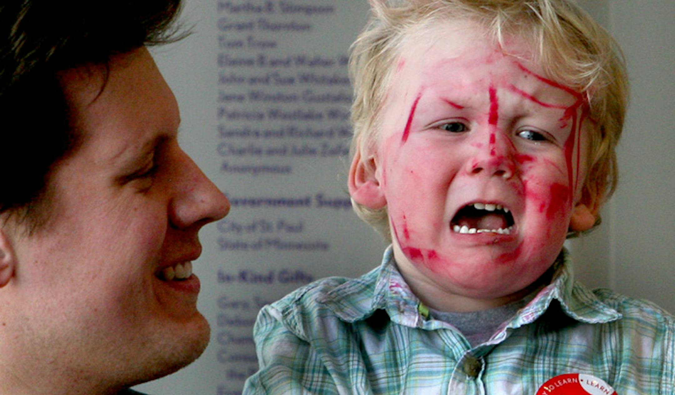 Two-year-old Drake Johnsrud, who had been having his face painted, loudly expressed his displeasure at having to leave the Minnesota Children's Museum on Sunday before he was ready. Dad Matt held him as a museum staffer, not pictured here, helped calm him down.