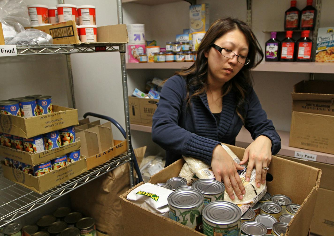 Jennifer Xiong, case worker level 2 at the Salvation Army on Payne Ave, filled orders for customers at the food shelf on 2/28/13. The Salvation Army appreciates all the cans of peas, baked beans and boxed cereal that is donated to their foodshelves. However, with a growing clientele who are Hmong and Latino, the charity has put out a call for food more agreeable to Asian and Hispanic diets. The Payne Ave location serves 40 to 50 households per day.] Bruce Bisping/Star Tribune bbisping@startribun