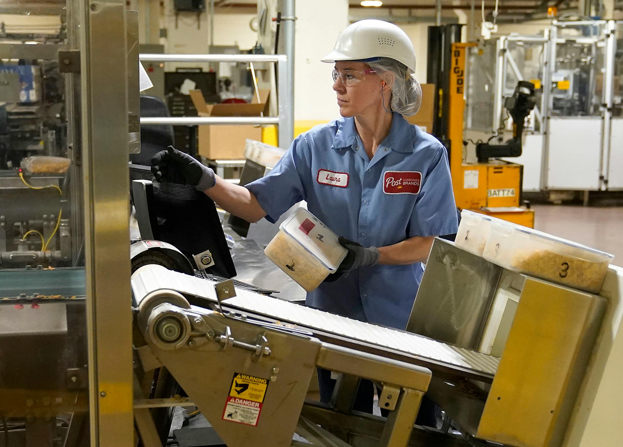 Laura Schuster, a packing specialist, runs a cereal control through a metal detector on the phase 10 cereal line at Post Consumer Brands.
