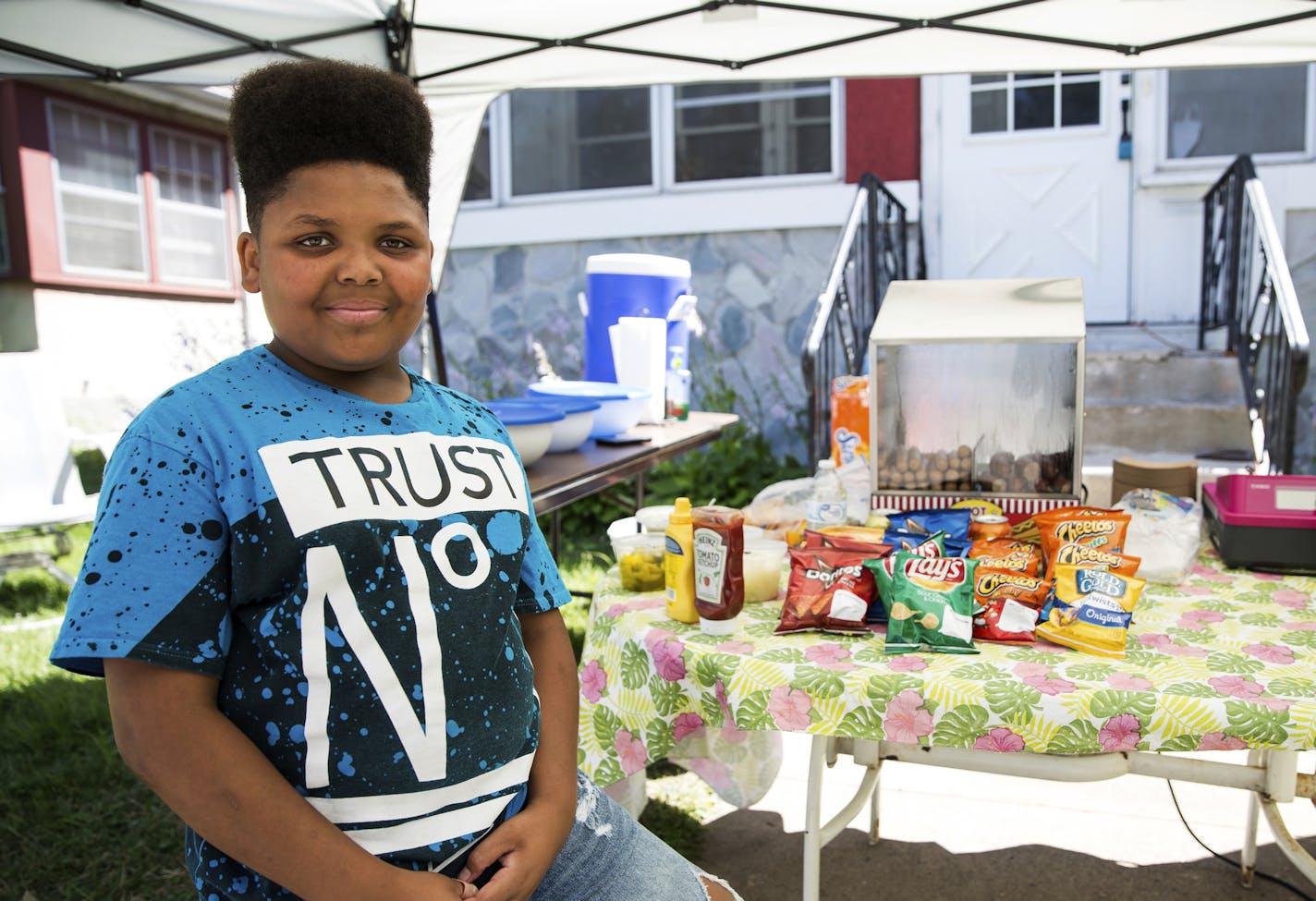 Jaequan Faulkner, 13, stands for a portrait in front of Jaequan's Old Fashioned Hot Dogs in north Minneapolis on Monday, July 16, 2018. The temporary stand, which sits on the steps of Faulkner's house on Penn Avenue, is now health department approved. (Lacey Young/Minnesota Public Radio via AP)