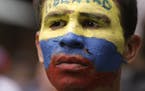 An opponent to Venezuela's President Nicolas Maduro, his face painted the colors of the Venezuelan national flag and with the Spanish word for "Freedo