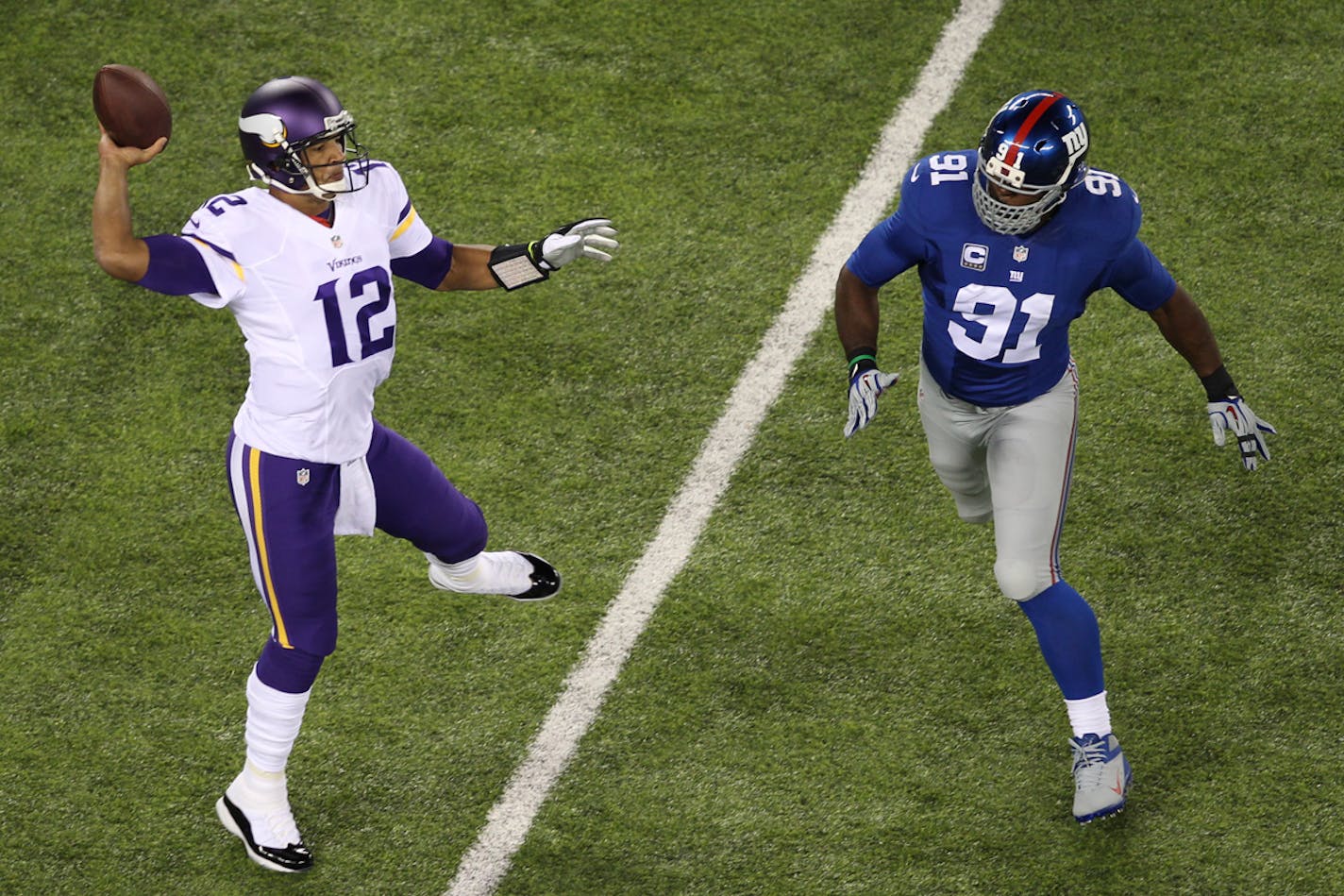 Minnesota Vikings quarterback Josh Freeman (12) throws a pass as New York Giants' Justin Tuck (91) closes in during the first half of an NFL football game Monday, Oct. 21, 2013 in East Rutherford, N.J.